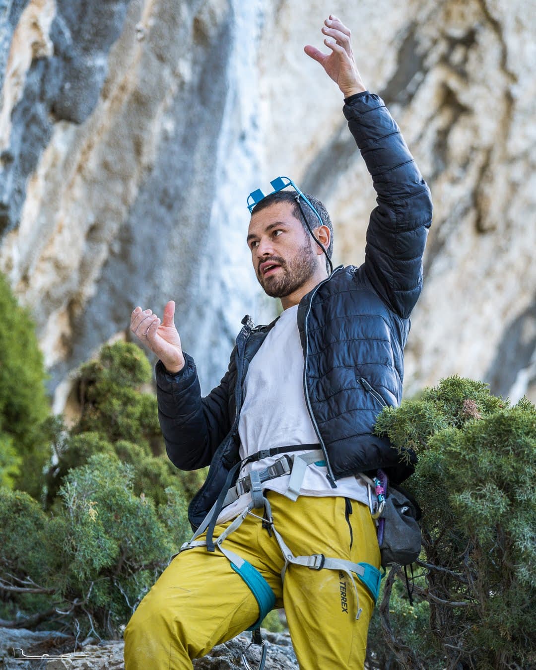 Portrait of Alejandro Cornejo at a climbing area in Peru, gesturing toward the rock.
